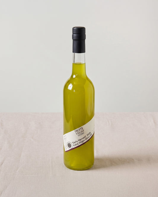 Bottle of Fourth Village Early Harvest Extra Virgin Olive Oil with a label on a light background