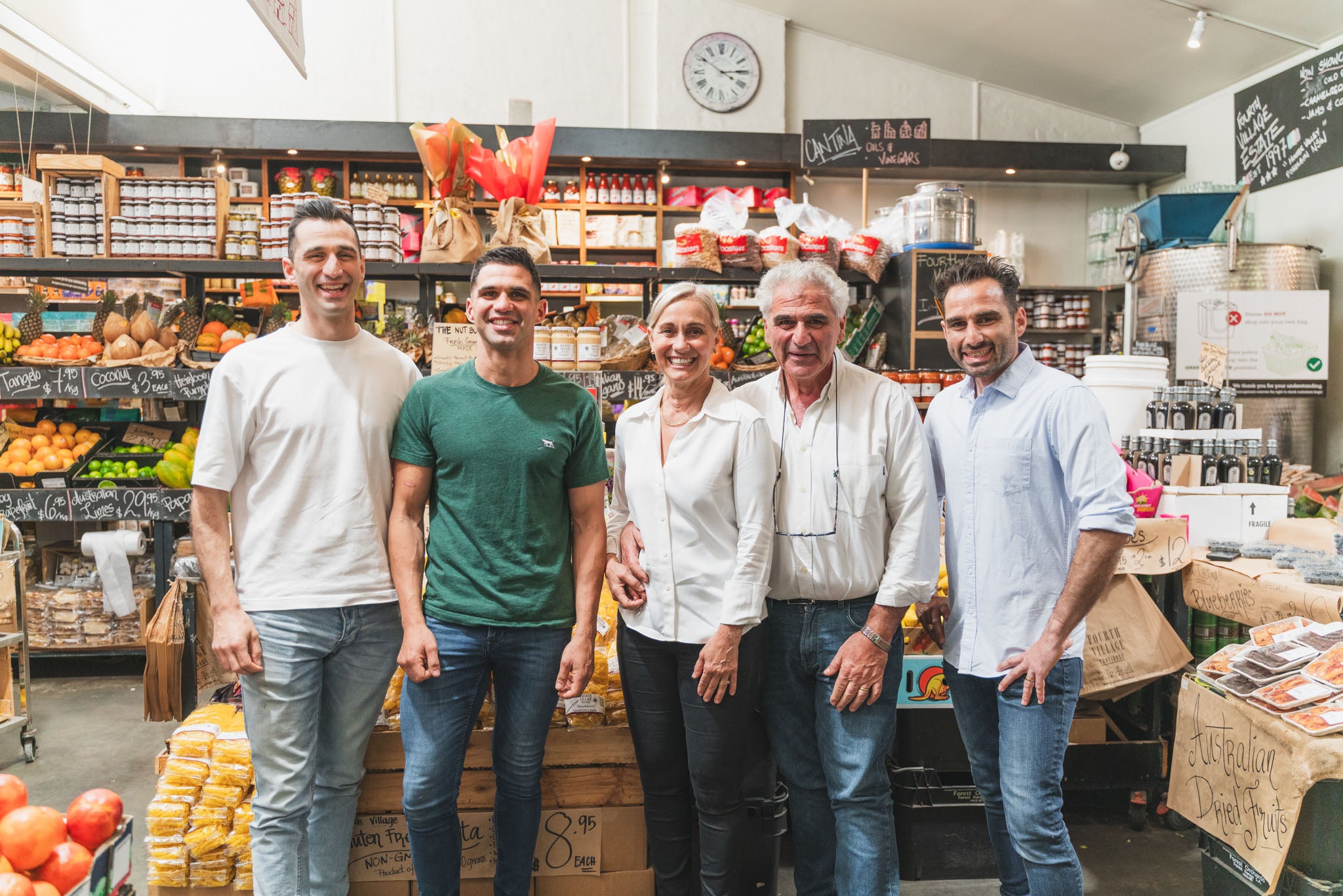 Group of five people standing in a grocery store with shelves and products in the background.